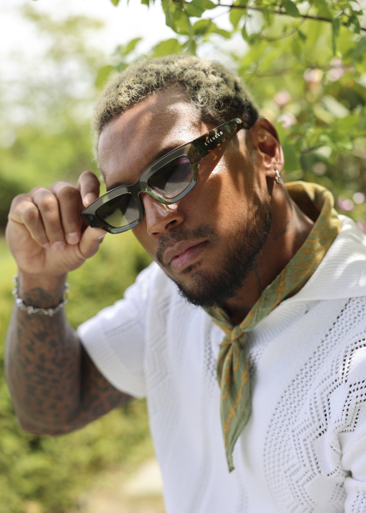 Person wearing EYENEED eyewear outdoors in a white polo